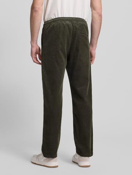 Männermodel trägt grüne Cordhose mit elastischem Bund Modell 'JABARI' von Samsøe Samsøe, Regular-Fit, Gesäßtasche, Ganzkörperansicht Rückansicht