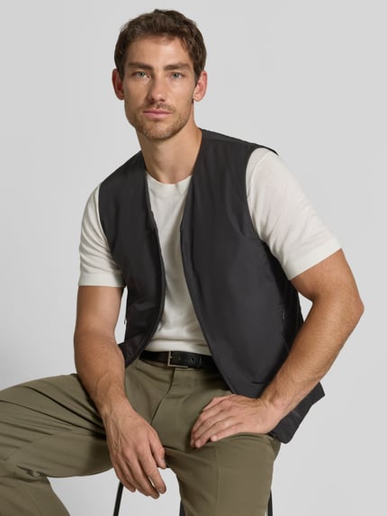 Männermodel trägt Regular Fit Weste mit V-Ausschnitt Modell 'Marve' von Tiger of Sweden in Dunkelgrau mit Reißverschluss und Eingrifftaschen, Ganzkörperansicht von vorne.