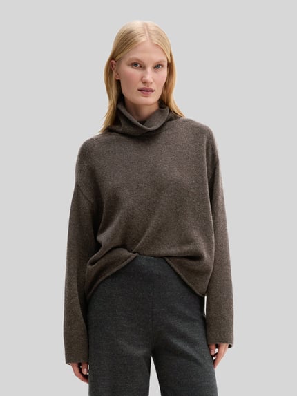 Frauenmodel trägt Rollkragenpullover mit überschnittenen Schultern von MARC O'POLO in unifarbenem dunkelbraun, Strukturstrick, Cropped Regular Fit, lange Ärmel, gerippte Bündchen, Label-Detail, Ganzkörperansicht von vorne.
