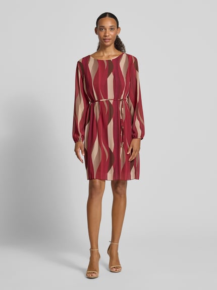 Frauenmodel trägt knielanges Kleid mit Bindegürtel Modell 'Sa44raa' von ZABAIONE, Chiffon, Allover-Muster in Rot und Beige, Rundhalsausschnitt, Plisseefalten, gerader Schnitt, Ganzkörperansicht von vorne.