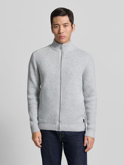 Mężczyzna nosi Regular Fit Strickjacke mit Woll-Anteil von Tom Tailor w odcieniu melanżu, długi rękaw, stójka, krój regular fit, widok z przodu na całą sylwetkę.