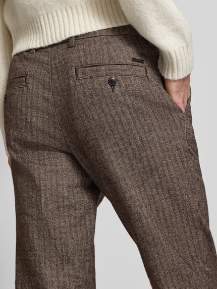 Männermodel trägt Regular Fit Hose mit Gesäßtaschen von JACK & JONES in Braun mit Bügelfalten, Detailaufnahme Rückansicht.