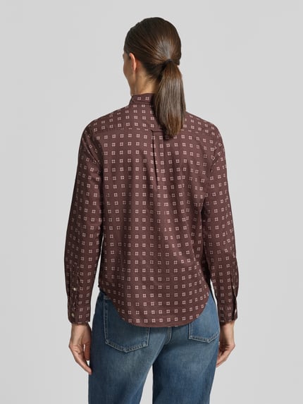 Frauenmodel trägt Longline Langarmbluse mit Label-Detail von GANT, geometrisches Allover-Muster, braun-weiß, Webware, Ganzkörperansicht Rückansicht.