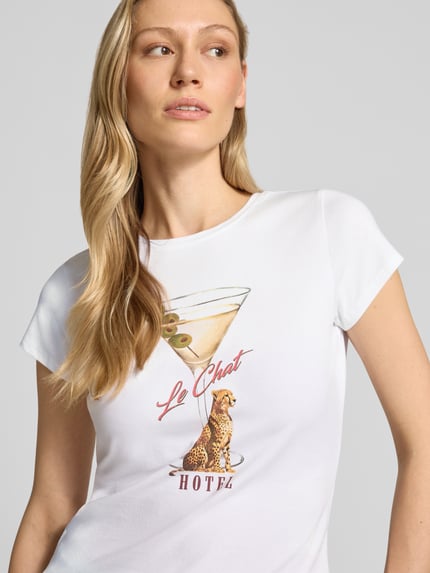 Frauenmodel trägt T-Shirt mit Label-Detail Modell 'LEOPARDTINI' von Guess, weiß, eng geschnitten, Rundhals, Nahaufnahme Oberkörper.