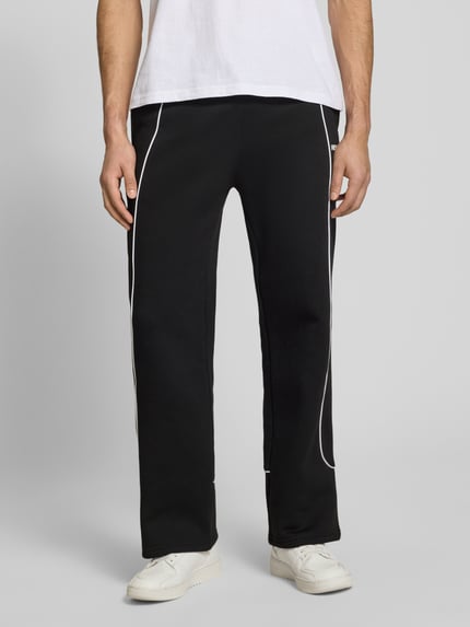 Männermodel trägt schwarze Sweatpants mit elastischem Bund und Logo von REVIEW aus reiner Baumwolle im Relaxed-Fit, Ganzkörperansicht von vorne. Innenbeinlänge bei Größe M: 78 cm.