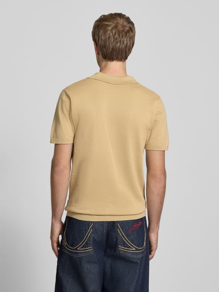 Männermodel trägt Regular Fit Poloshirt in Strick-Optik Modell 'Bray' von Blend, beige, reine Baumwolle, kurzärmelig, Ganzkörperansicht Rückansicht.