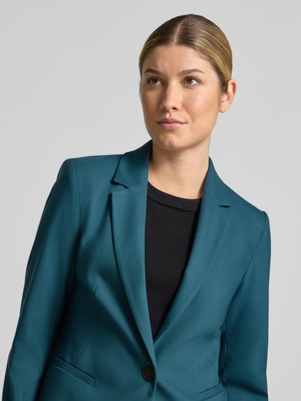 Frauenmodel trägt Slim Fit Blazer mit Paspeltaschen von COMMA, petrolfarben, glatte Textur, Reverskragen, Nahaufnahme Oberkörper.