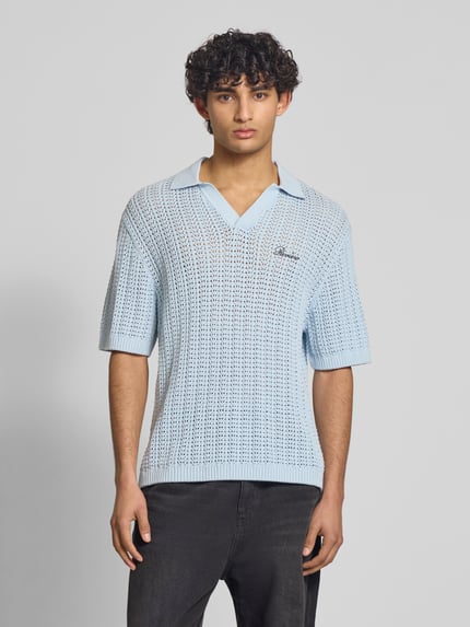 Mężczyznę model nosi Slim Fit Poloshirt in Crochet-Optik od REVIEW z bawełny, krój slim fit, kołnierzyk polo, rękaw o dł. 1/2, wyhaftowane logo, długość tyłu w rozmiarze M: 68 cm, jasnoniebieski, strukturalna faktura, całkowity widok z przodu.
