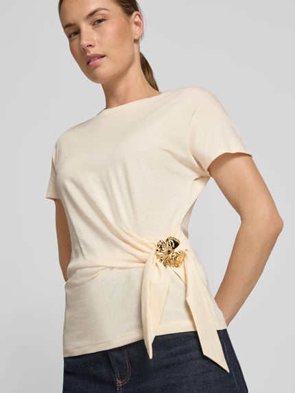 Vrouwenmodel draagt T-Shirt in Wickel-Optik mit Brosche van Christian Berg Woman Selection, effen crème katoen, regular fit, ronde hals, detailopname bovenlichaam.