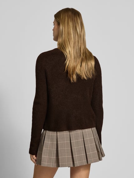Frauenmodel trägt Cardigan mit Label-Patch von ONLY in unifarbenem Dunkelbraun und Strickoptik, ganzkörperansicht rückansicht.
