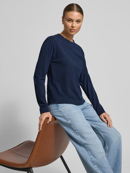 Frauenmodel trägt Longsleeve mit geripptem Rundhalsausschnitt von Skiny, Baumwoll-Elasthan-Mix, Regular Fit, Label-Detail, Ganzkörperansicht von vorne. Rückenlänge bei Größe 36: 60 cm, dunkelblau, glatte Textur, helle Jeans.