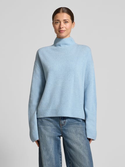 Frauenmodel trägt Strickpullover mit Stehkragen von Christian Berg Woman aus reiner Baumwolle, hellblau, Regular Fit, weite Ärmel, Ganzkörperansicht von vorne.