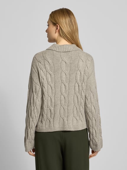 Vrouwenmodel draagt gebreide pullover met kabelpatroon, model 'Pavana Peony' van MSCH Copenhagen, materiaalmix met katoen, relaxed fit, platte kraag, druppelvormige hals, ruglengte maat S/M 52 cm, mouwlengte 52 cm, kleuren beige en groen; geheelachteraanzicht.