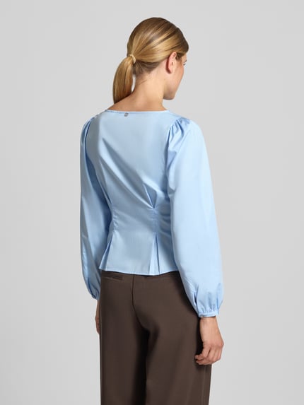 Vrouwenmodel draagt Bluse aus reiner Baumwolle mit Knopfleiste van Rich & Royal in lichtblauw, boothals, getailleerde pasvorm, stolpplooien, elastische mouwboorden, ruglengte 51 cm bij maat 36, mouwlengte 62 cm, puur katoen, achteraanzicht hele lichaam.