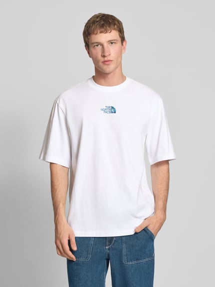 Männermodel trägt Oversized T-Shirt mit Logo und Rundhalsausschnitt von The North Face aus reiner Baumwolle, weiß, Ganzkörperansicht von vorne.