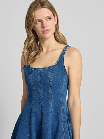 Frauenmodel trägt A-Linie Jeanskleid aus reiner Baumwolle Modell 'GADEME' von Hugo Blue in Denim-Optik mit Karree-Ausschnitt, Nahaufnahme Oberkörper.