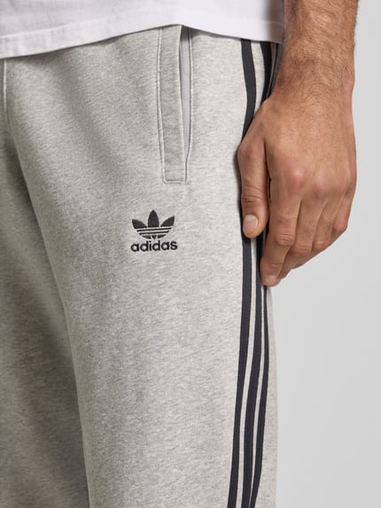 Männermodel trägt Sweatpants mit elastischem Bund von adidas Originals aus Baumwoll-Mix, Lockerer-Schnitt, Label-Stitching, Eingrifftaschen, Nahaufnahme Oberkörper.