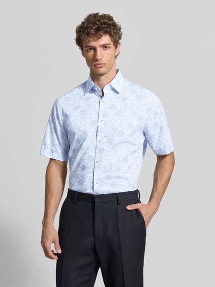 Männermodel trägt Modern Fit Business-Hemd mit Kentkragen von OLYMP, floraler Print in Hellblau, reine Baumwolle, Nahaufnahme Oberkörper.