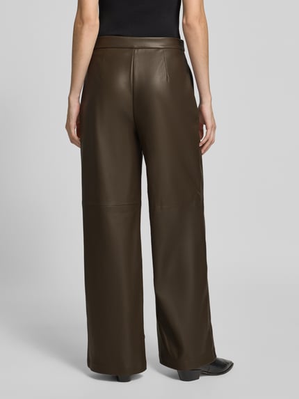 Frauenmodel trägt Regular Fit Lederhose mit Bundfalten von STEFANEL in unifarbener Lederoptik mit Teilungsnähten, Ganzkörperansicht Rückansicht.