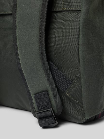 Produktfoto, detailreiche Nahaufnahme grüner Stofftextur mit Gurt aus dem Rucksack mit Label-Patch Modell 'FIELD WAX' von Barbour, Herren Rucksack von Barbour