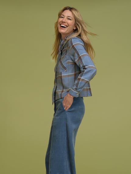 Frauenmodel trägt Regular Fit Schluppenbluse mit Brusttasche von MORE & MORE, kariertes Muster in Blau- und Brauntönen, Ganzkörperansicht von vorne, Kontext: Damen Schluppenbluse, Schluppe, aufgesetzte Brusttasche, durchgehende Knopfleiste, langärmliges Design, Rückenlänge 59 cm, Ärmellänge 65 cm.