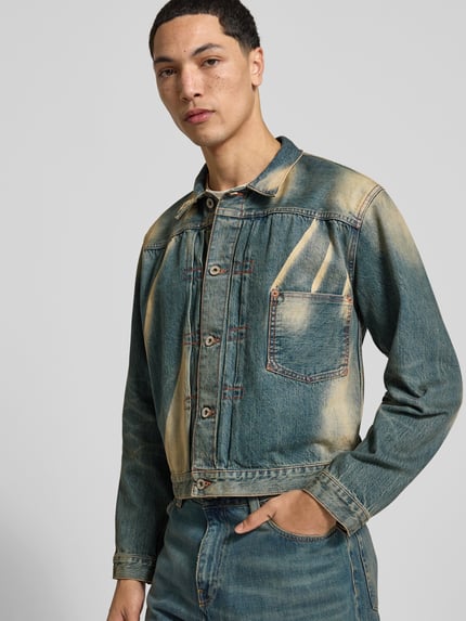 Męski model ma na sobie Regular Fit Jeansjacke aus Baumwolle od KENZO, bawełna, krój regular fit, efekt znoszenia, nakładana brustasza, listwa guzikowa na całej długości, długość tyłu w rozmiarze M: 58 cm, szerokość ramion w rozmiarze M: 48 cm, długość rękawów w rozmiarze M: 63 cm, odcienie niebieskiego z przetarciami, tekstura jeansu, Ganzkörperansicht od przodu.