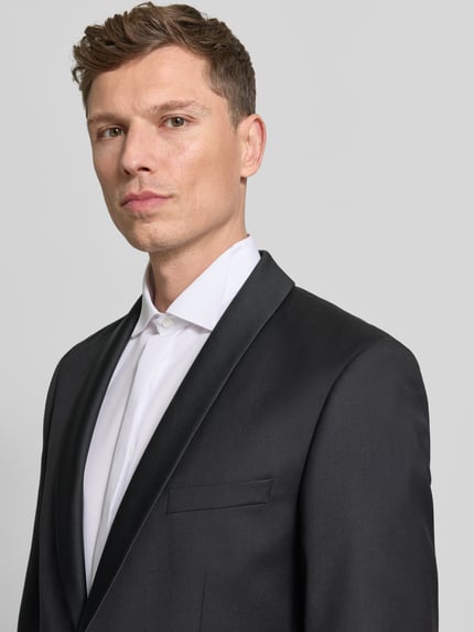 Männermodel trägt 1-Knopf-Sakko mit Reverskragen von Wilvorst aus schwarzem Baumwoll-Mix mit Pattentaschen, Nahaufnahme Oberkörper.
