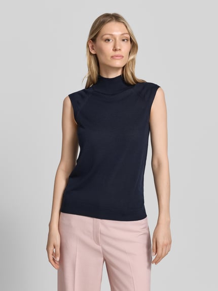 Frauenmodel trägt Slim Fit Pullunder aus reiner Schurwolle Modell 'FIPINI' von BOSS in Dunkelblau zu rosa Hose, Damen, Ganzkörperansicht von vorne.