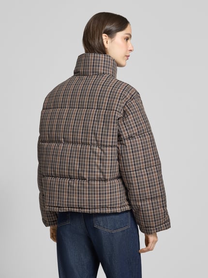 Frauenmodel trägt Steppjacke mit Stehkragen Modell 'LAURI' von MANGO, kariertes Muster, beige-braune Farbtöne, Ganzkörperansicht Rückansicht. Damen Steppjacke, Regular Fit, Reißverschluss, Eingrifftaschen, Allover-Look. Rückenlänge 60 cm, Schulterbreite 53 cm, Brustweite 60 cm, Ärmellänge 60 cm.