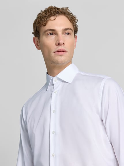 Männermodel trägt Regular Fit Business-Hemd mit Kentkragen von Christian Berg Men aus Reine Baumwolle, glatte Struktur, Nahaufnahme Oberkörper. Rückenlänge 78 cm, Schulterbreite 45 cm, Ärmellänge 65 cm bei Größe 39/40.