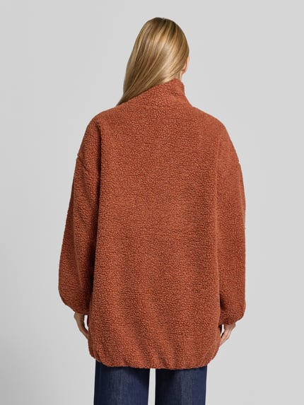 Frauenmodel trägt Oversized Jacke mit Stehkragen Modell 'Hoktown' von American Vintage in rostbraunem Fleece, Ganzkörperansicht Rückansicht. Rückenlänge, Schulterbreite, Brustweite und Ärmellänge modellabhängig, locker geschnittene Textur.