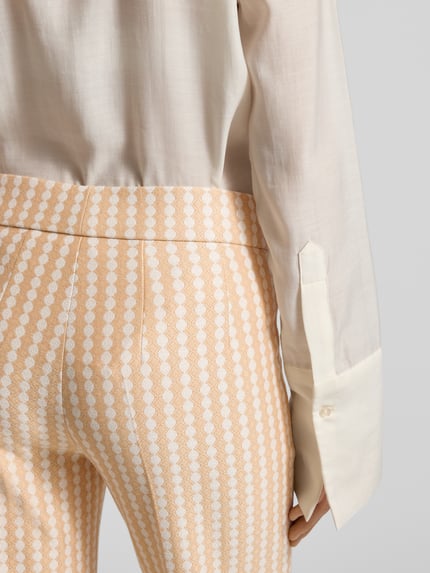 Frauenmodel trägt Stoffhose in verkürzter Passform Modell 'NANETTE' von SEDUCTIVE in Creme und Apricot mit Muster, Nahaufnahme Hüfte, Viskose-Mix mit Stretch-Anteil, lockerer Schnitt, elastischer Bund, Bundfalten