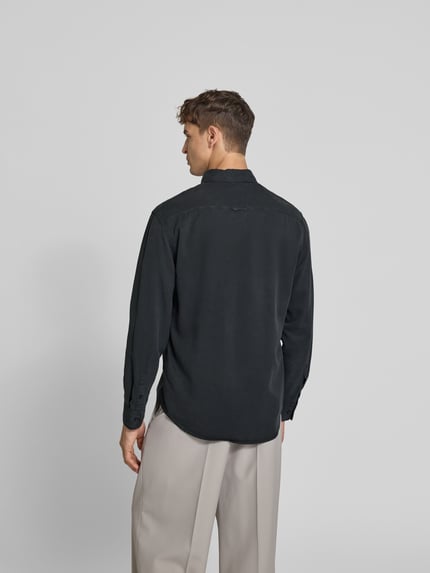 Männermodel trägt Regular Fit Freizeithemd aus Lyocell von Filippa K in Schwarz, glatte Textur, Rückenansicht, Ganzkörperansicht Rückansicht.