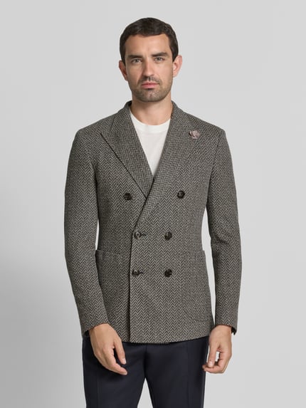 Männermodel trägt Slim Fit Sakko mit Reverskragen Modell 'Heazy' von JOOP! COLLECTION im Zweireiher-Design, Material-Mix mit Viskose-Anteil, dezentes Fischgrätmuster in Braun-Grau mit dunklen Knöpfen, AufgesetzteTaschen, Rückenlänge 75 cm, Schulterbreite 46 cm, Ärmellänge 68 cm, Ganzkörperansicht von vorne.