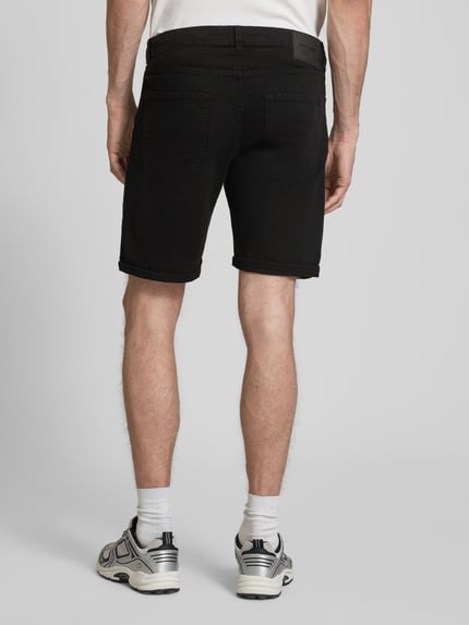 Männermodel trägt schwarze Jeansshorts mit Umschlag und Eingrifftaschen, Modell 'RICK ALLEN' von Jack & Jones, Rückansicht Ganzkörperansicht. Regular Fit, Baumwoll-Elasthan-Mix, Kontext: Bundweite M 43 cm, Innenbeinlänge M 20 cm.