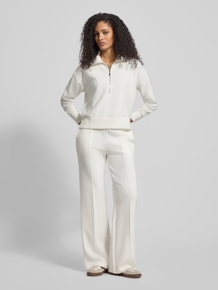 Frauenmodel trägt Sweatshirt mit Umlegekragen von Christian Berg Woman im Material-Mix mit Modal-Anteil, lockerer Schnitt, Reißverschluss, gerippte Abschlüsse, cremefarben, glatte Textur, Ganzkörperansicht von vorne.