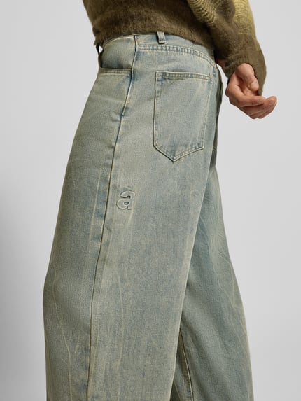 Männermodel trägt Wide Fit Jeans im Used-Look von ANOTHER COTTON LAB, Baumwoll-Mix mit Viskose-Anteil, Eingrifftaschen, Nahaufnahme Oberkörper.