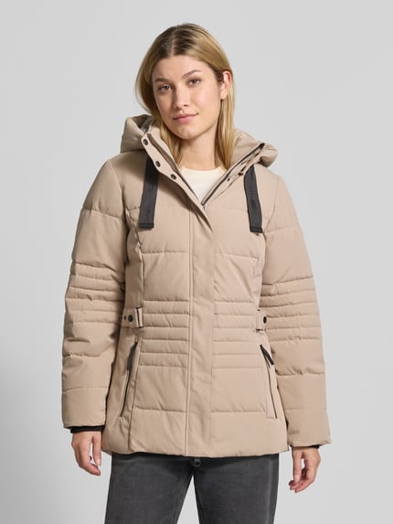 Frauenmodel trägt Jacke mit Kapuze und Label-Patch von G.I.G.A. DX in Beige, Material-Mix, seitliche Reißverschlusstaschen, Ganzkörperansicht von vorne.