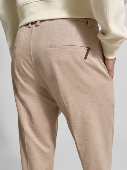 Männermodel trägt Regular Fit Hose aus Viskose-Mix Modell 'CIJUNO-O' von CINQUE in Beige mit Bundfalten, Detailaufnahme Rückansicht.