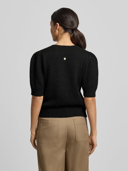 Frauenmodel trägt Strickpullover mit gerippten Abschlüssen Modell 'Kylie' von JOOP!, lockerer Schnitt, Halbarm, Ganzkörperansicht Rückansicht.