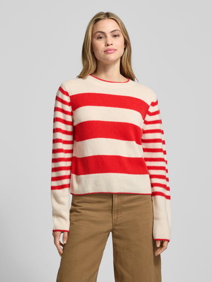 Vrouwenmodel draagt Regular Fit Strickpullover aus reiner Schurwolle van Marc O'Polo, wol, rood-beige gestreept, crew neck, lange mouw, ribboorden, all-over patroon, volledige lichaamsweergave van voren.