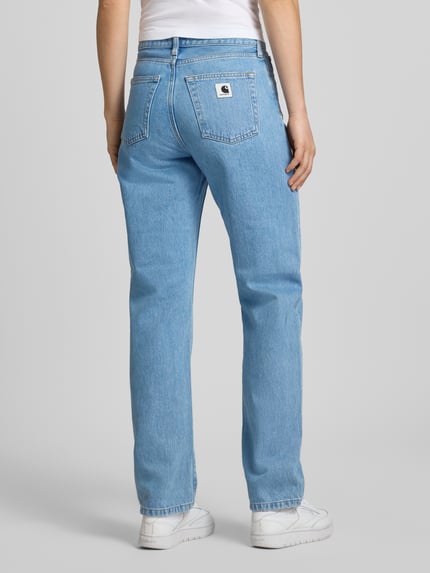 Frauenmodel trägt Straight Leg Jeans im 5-Pocket-Design Modell 'Noxon' von Carhartt Work In Progress aus gewachster Baumwolle in Hellblau, Ganzkörperansicht Rückansicht.