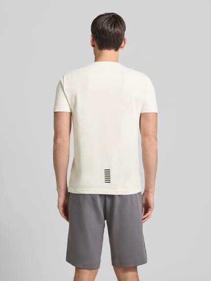Männermodel trägt T-Shirt mit Label-Print von EA7 Emporio Armani aus Baumwoll-Elasthan-Mix, Slim-Fit, Rückansicht, Rückenlänge 68 cm.
