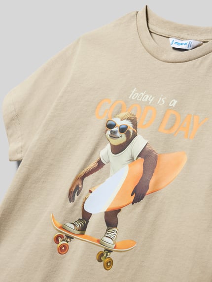 Mädchen trägt Kinder T-Shirt aus reiner Baumwolle von Mayoral, sandfarben, mit Aufdruck, gerader Schnitt, Rundhalsausschnitt, kurzärmelig, Ganzkörperansicht von vorne.