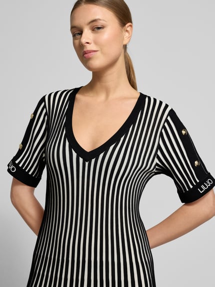 Vrouwenmodel draagt Mini-jurk met geribde boorden van LIU JO SPORT in zwart-wit viscosemix, labelprint, getailleerd model, V-hals, bovenlichaam close-up.