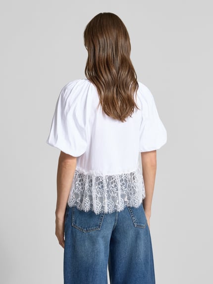 Frauenmodel trägt T-Shirt mit Spitze und Ballonärmeln von Rich & Royal in Weiß, Reine Baumwolle, Straight Fit, Rückenlänge 56 cm, Ganzkörperansicht Rückansicht.