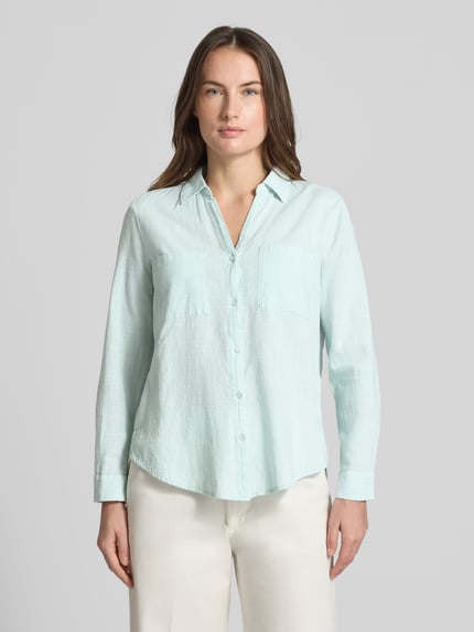 Frauenmodel trägt Regular Fit Hemdbluse aus reiner Baumwolle von Tom Tailor in Hellblau mit Hemdkragen, feiner Webstruktur, Ganzkörperansicht von vorne.