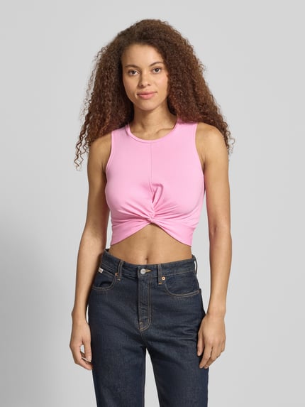 Vrouwenmodel draagt Crop Top met Knotendetail model 'TWIGGI' van Noisy May, roze katoenmix met stretch, cropped fit, ronde hals, detailopname bovenlichaam, context: ruglengte maat S 37 cm.