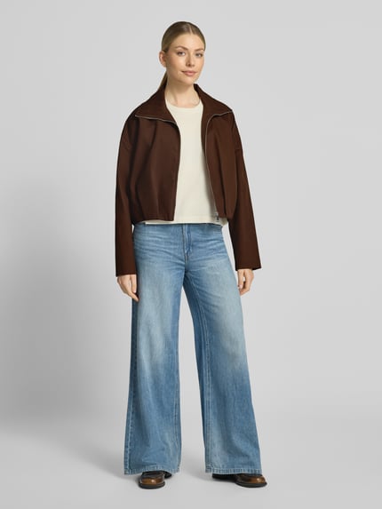 Frauenmodel trägt braunen Blouson mit Umlegekragen Modell 'DANTES' von MANGO aus Baumwolle, dazu helle Jeans, Ganzkörperansicht von vorne.
