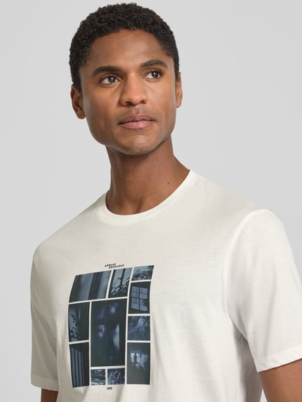 Męski model trägt Slim Fit T-Shirt mit Motiv-Print von Armani Exchange aus bawełna, okrągły dekolt, długość tyłu w rozmiarze M: 70 cm, Nahaufnahme Oberkörper.